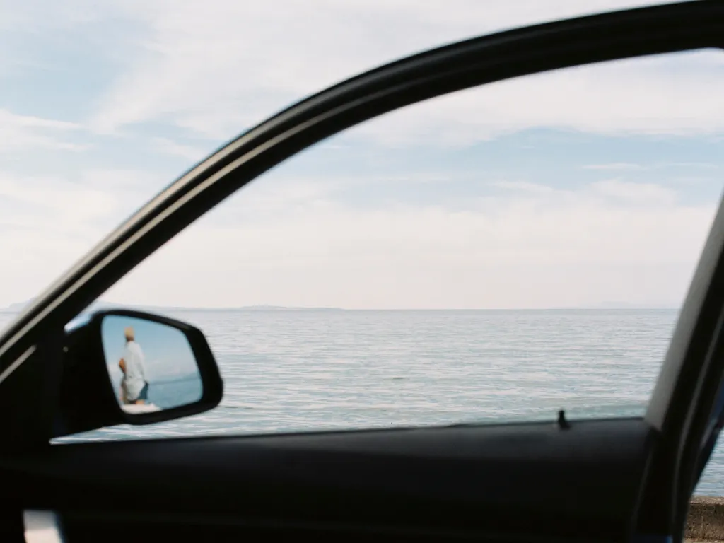 An image of the ocean, shot through a car window.