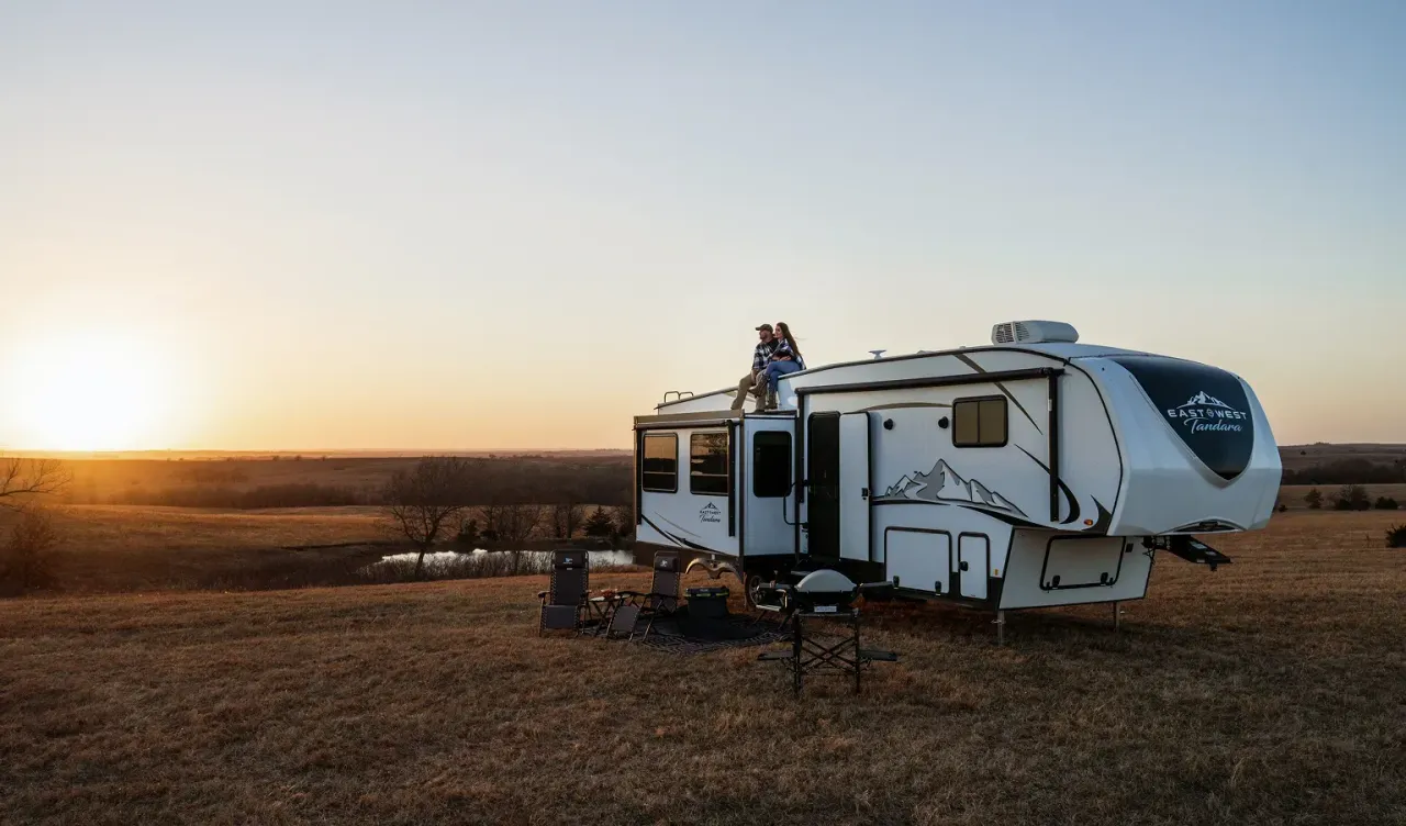 Two people sitting on the roof of their RV enjoying the sunset.