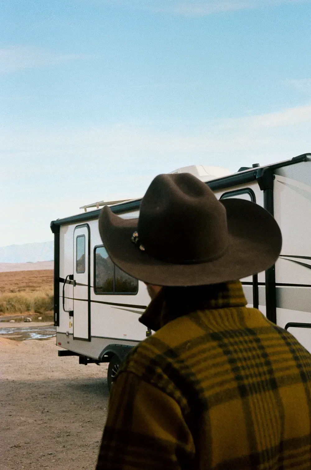 Person in a wide brimmed hat looking at an RV