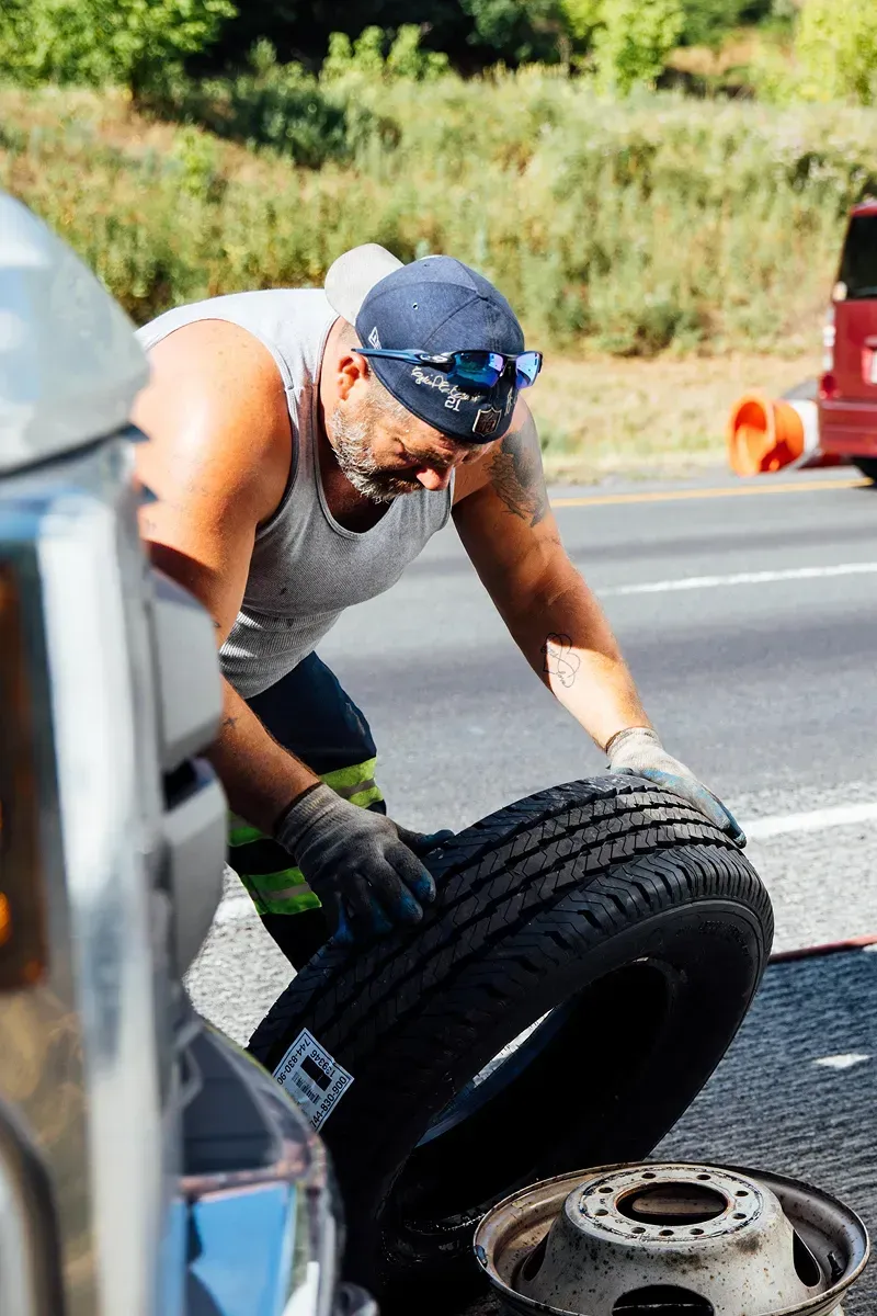 A mechanic inspecting a tire on the side of the road