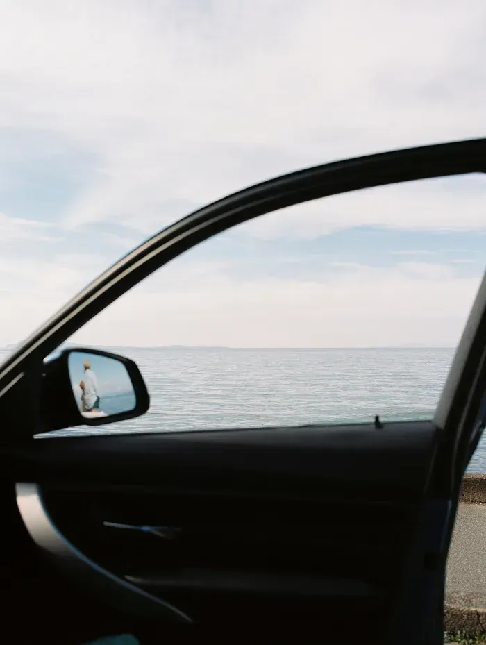 A vehicle door open to show a body of water in the background