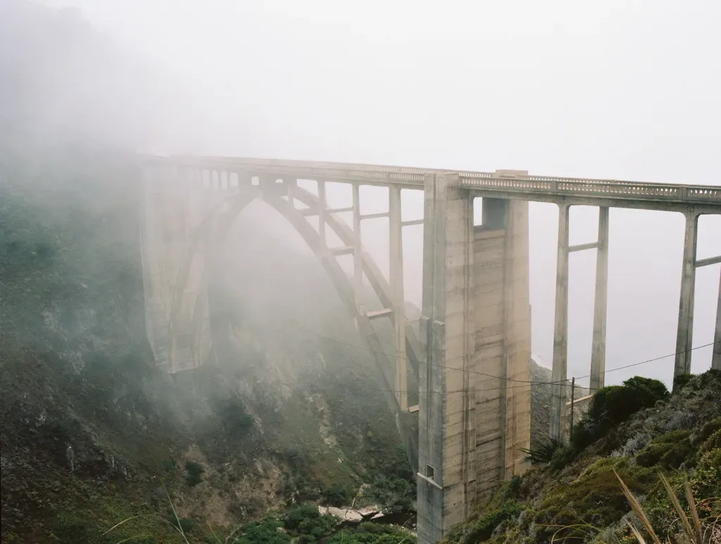 A tall bridge is covered in fog.