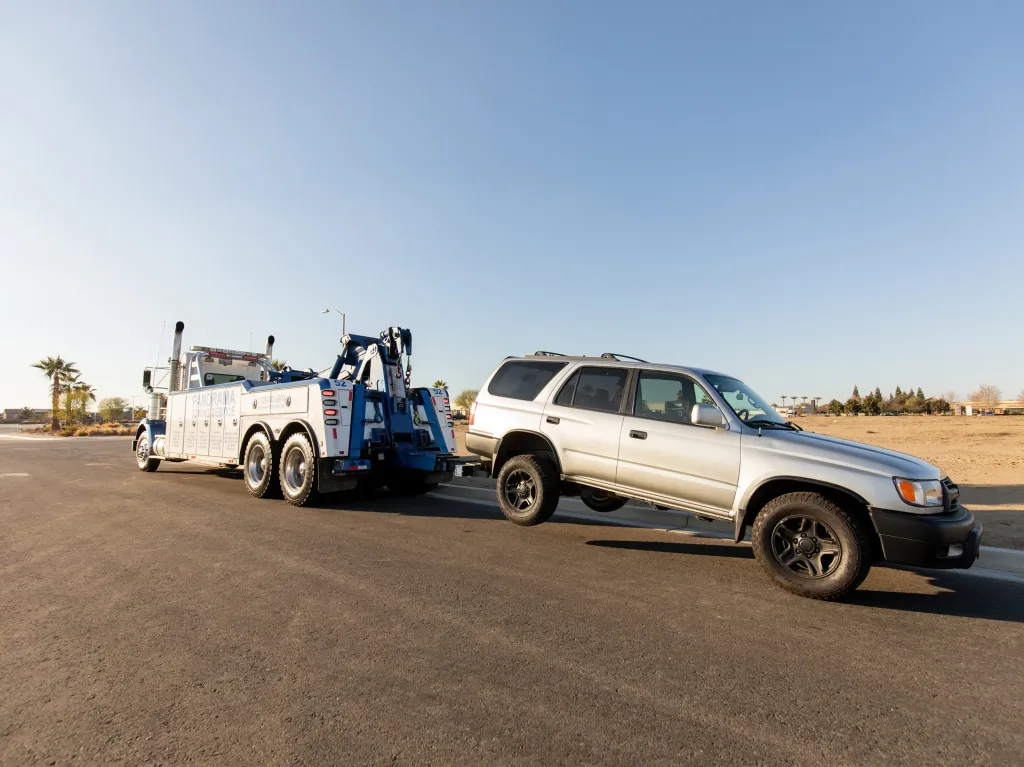 A tow truck pulls a vehicle down a road.